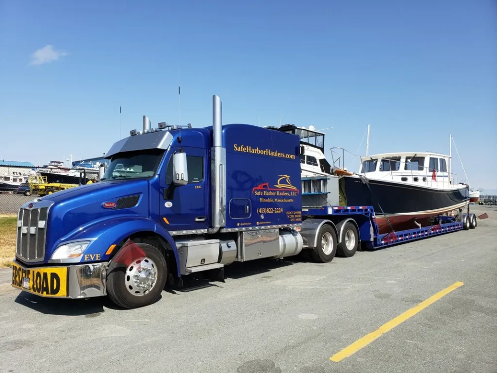 Duffy 35 vessel securely mounted on a custom transport trailer attached to a professional hauler in a dockyard setting.